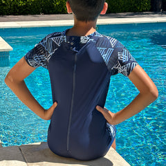 model wearing swimsuit next to swimming pool - back view