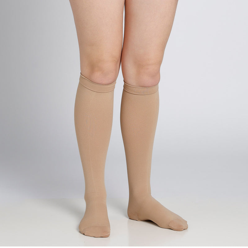 Beige knee-high socks worn by a person on a plain background